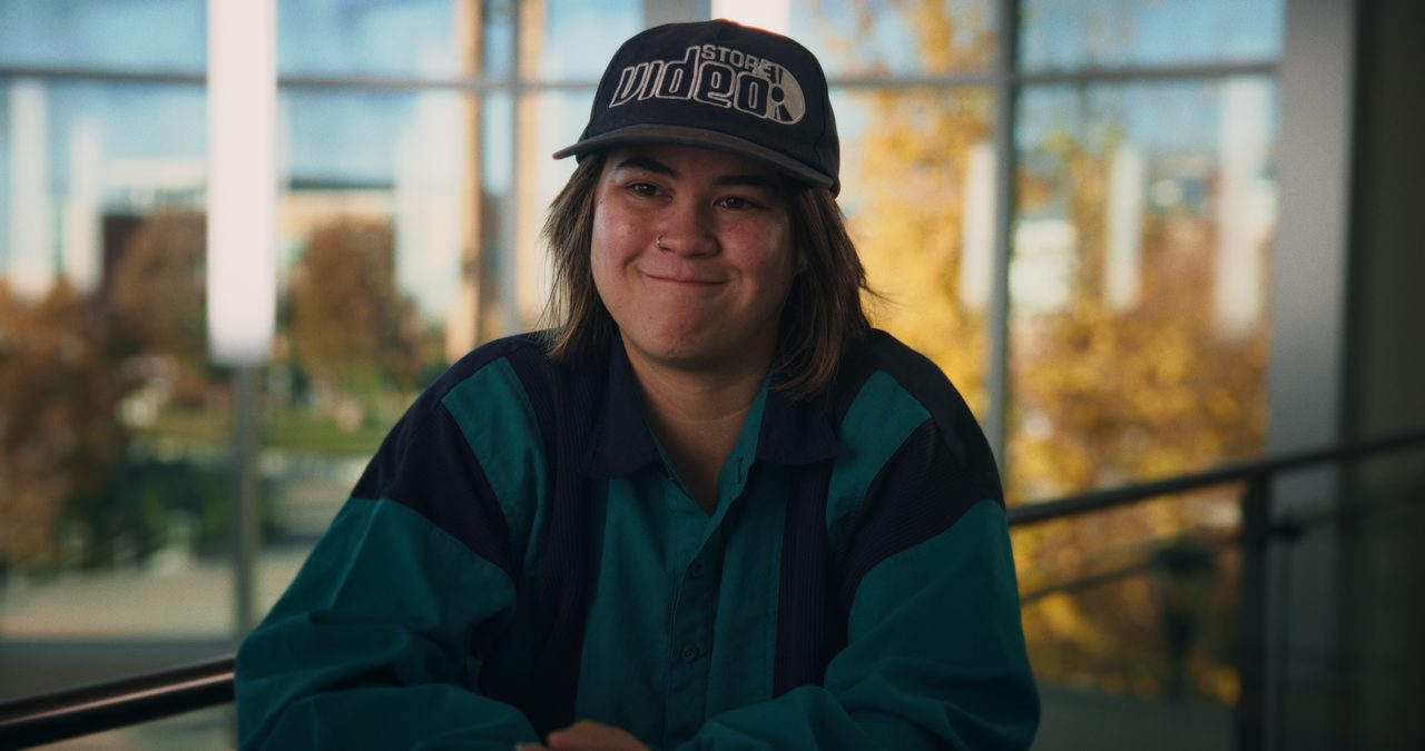 Chloe, smiling in a cap, framed against a window