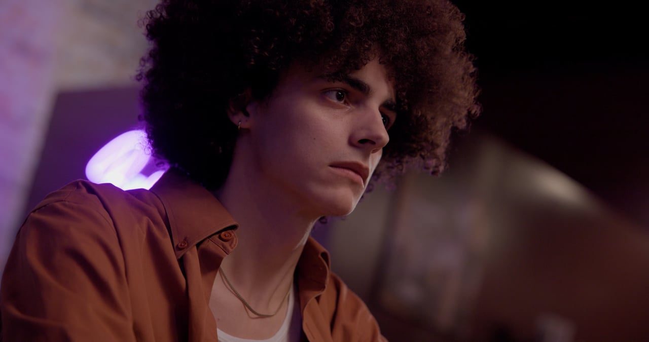 A young man with curly hair in purple light